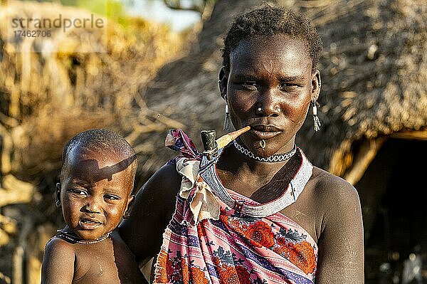 Frau vom Stamm der Toposa mit ihrem Baby beim Rauchen einer Pfeife  Ost-Äquatoria  Südsudan  Afrika