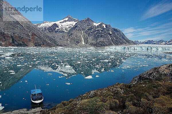 Kleines Boot im ruhigen Wasser eines Fjordes  Eisberge und karge Berge spiegeln sich im Wasser  Gletscher  Wildnis  Knud Rasmussen Glacier  Nordamerika  Grönland  Dänemark  Nordamerika