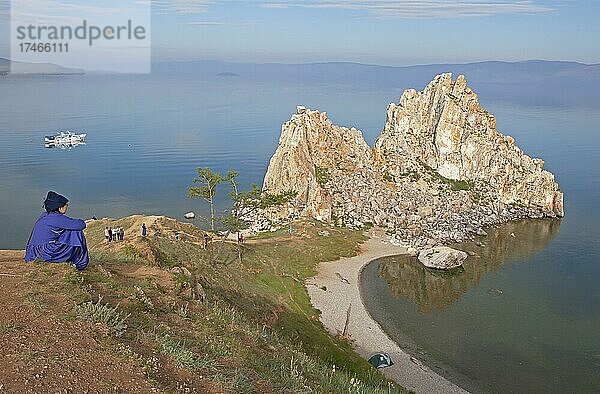 Frau in Tracht blickt auf den Schamanenfels im Baikalsee  Chuschir  Insel Olchon  Pribaikalsky Nationalpark  Provinz Irkutsk  Sibirien  Russland  Europa