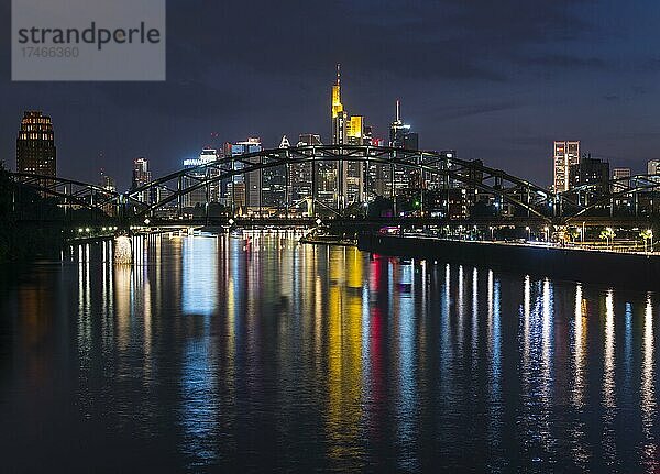 Bunt strahlende Skyline durch Deutschherrnbrücke spiegelt sich im Main während der späten Abenddämmerung  blaue Stunde  vom Arthur-von-Weinberg-Steg aus  Frankfurt am Main  Hessen  Deutschland  Europa