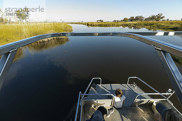 Ein Junge auf einem Motorboot fährt auf einer Wasserstraße im Okavango-Delta