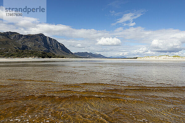 Breiter Sandstrand  seichtes Wasser  Blick auf die Küste.