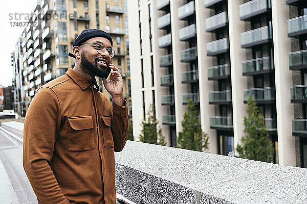 Lächelnder Mann  der in der Stadt mit dem Handy telefoniert