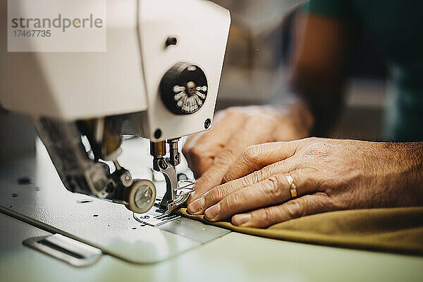 Modedesigner näht Kleidung an Maschine in Werkstatt
