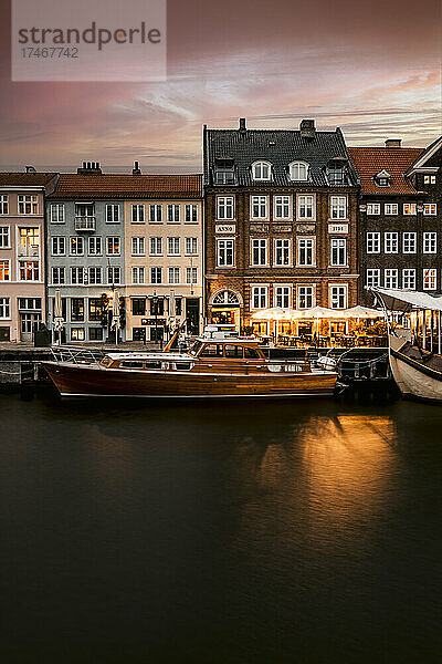 Häuser mit Booten  die in der Abenddämmerung im Nyhavn-Kanal festgemacht haben  Kopenhagen  Dänemark
