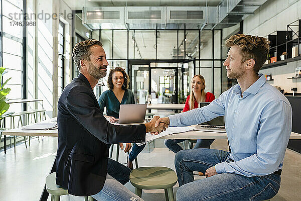 Geschäftsleute schütteln sich beim Treffen mit Kollegen im Büro die Hand