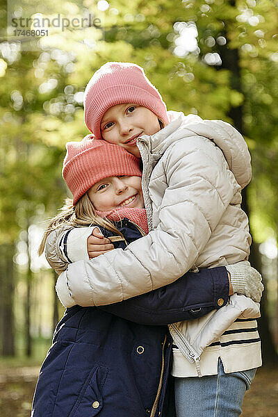 Mädchen mit Strickmütze umarmen sich im Park