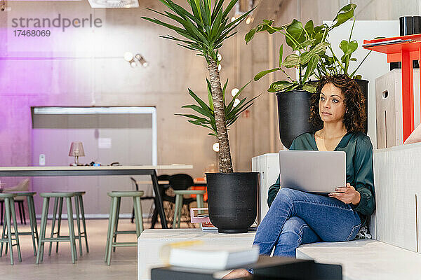 Geschäftsfrau mit Laptop sitzt im Büro