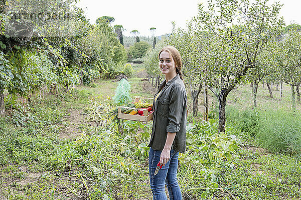 Lächelnde Bäuerin mit Gemüse im Gemeinschaftsgarten