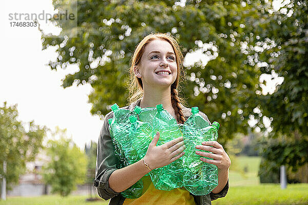Lächelnde Umweltschützerin mit grünen Flaschen  die wegschaut
