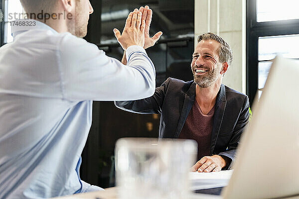 Glücklicher Geschäftsmann  der seinem Kollegen bei einem Treffen ein High-Five gibt
