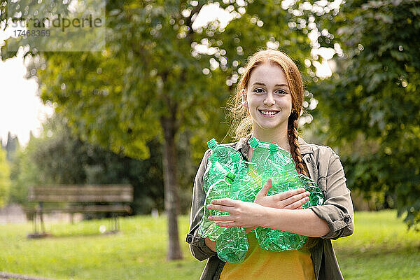 Lächelnde Freiwillige halten Plastikflaschen im Garten