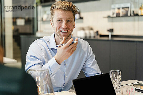 Lächelnder junger Geschäftsmann diskutiert mit Kollegen im Büro
