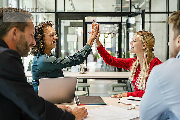 Geschäftsfrauen geben High-Five bei Treffen mit Kollegen im Büro