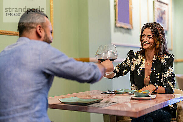 Glückliches Paar prostet im Restaurant mit Weingläsern an