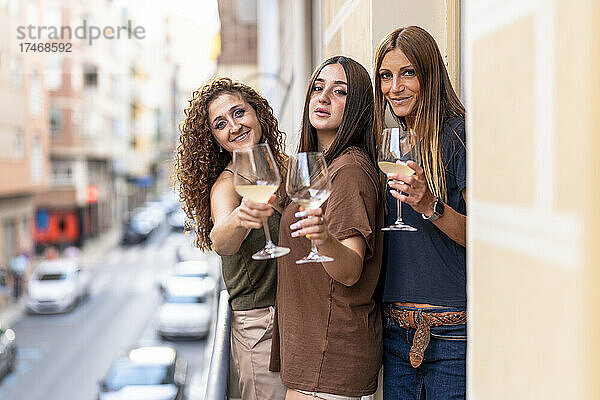 Freundinnen halten Weingläser auf dem Balkon