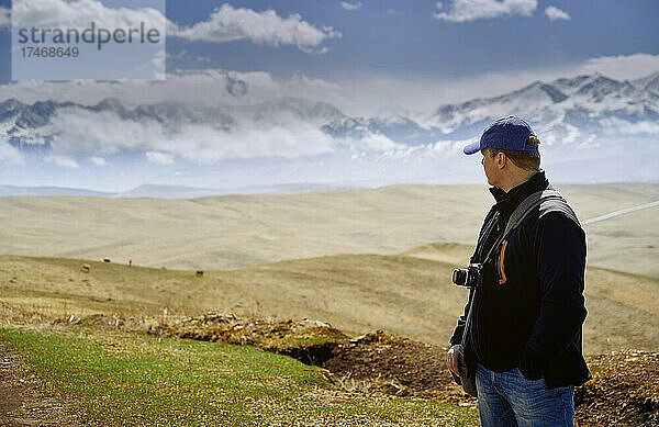 Mann mit Kamera blickt auf Berge