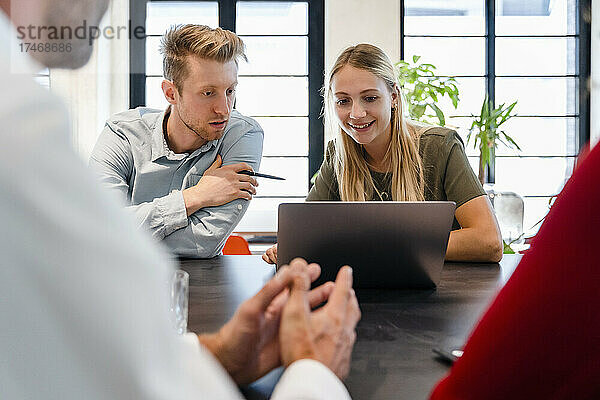 Junge Kollegen diskutieren am Laptop bei einer Besprechung im Büro