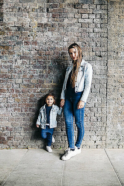 Mutter und Tochter stehen zusammen vor einer Mauer