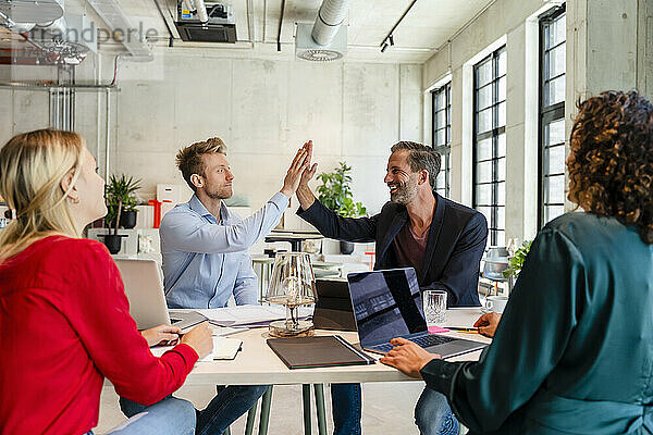 Geschäftsleute geben High-Five bei Treffen mit Kollegen im Büro