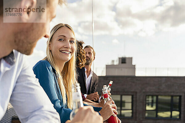 Junge Geschäftsfrau trinkt mit Kollegen auf dem Dach