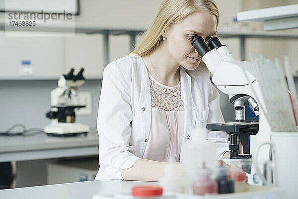 Blonde Wissenschaftlerin forscht unter dem Mikroskop im Labor