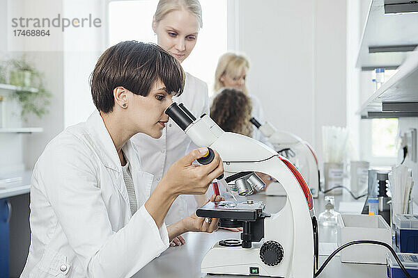 Wissenschaftler prüfen Probe durch Mikroskop im Labor