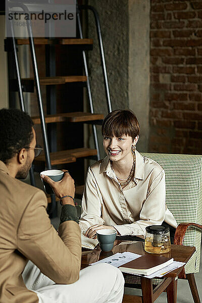 Fröhliches Teenager-Mädchen  das mit seinem Freund im Café spricht und Tee trinkt