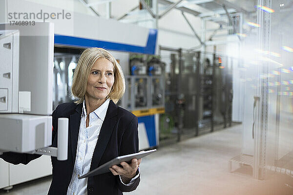 Reife Geschäftsfrau mit digitalem Tablet  die in der Fabrik arbeitet