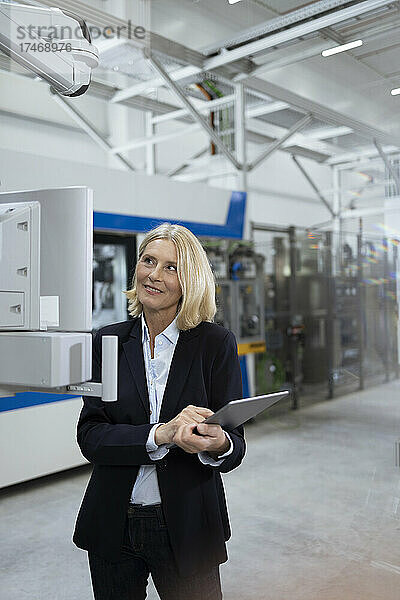 Weibliche Fachkraft mit digitalem Tablet untersucht Maschinen in der Fabrik