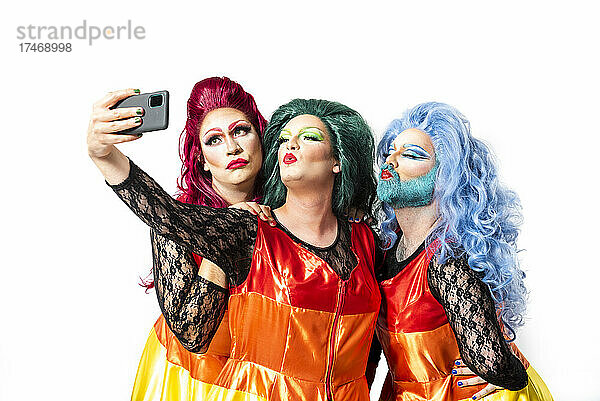 Drag Queens machen ein Selfie mit dem Smartphone vor weißem Hintergrund