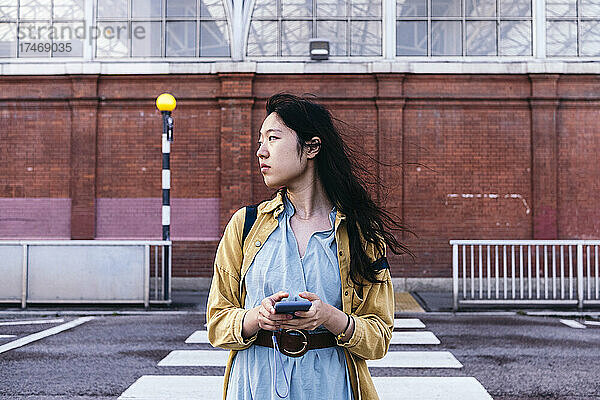 Frau mit Mobiltelefon überquert Straße