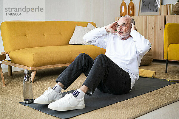Älterer Mann macht zu Hause Sit-ups auf der Trainingsmatte