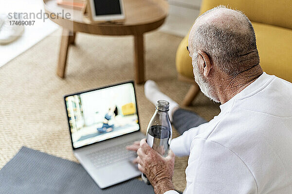 Mann schaut sich zu Hause Online-Yoga-Tutorial auf Laptop an