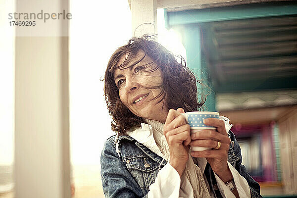 Lächelnde Frau hält Kaffeetasse in Hütte