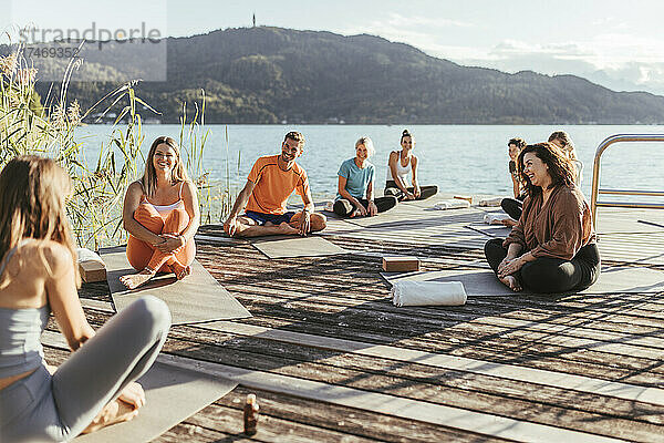 Männer und Frauen unterhalten sich während des Yoga-Kurses mit einer Lehrerin