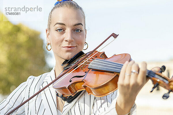 Lächelnder junger Musiker  der Geige spielt