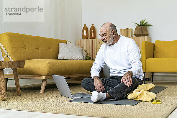 Älterer Mann schaut sich zu Hause Tutorial auf Laptop an