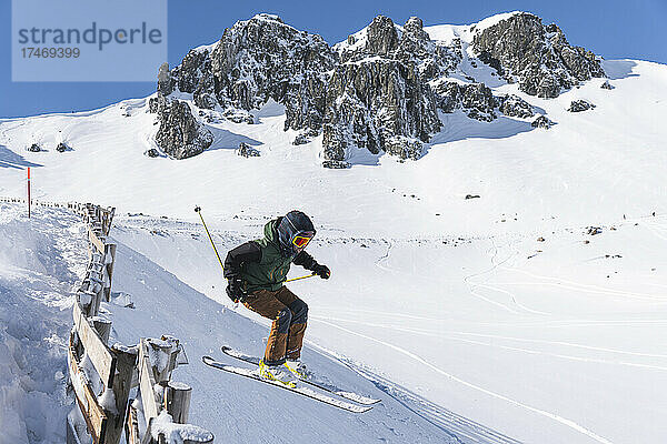 Junger Tourist fährt auf schneebedecktem Berg Ski