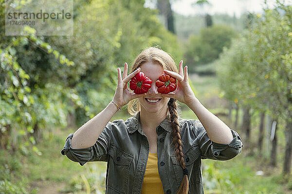 Verspielte Bäuerin hält Tomaten vor Augen