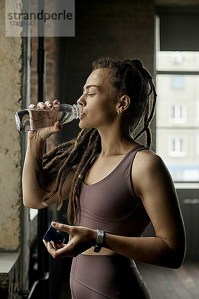 Sportlerin trinkt Wasser im Fitnessstudio