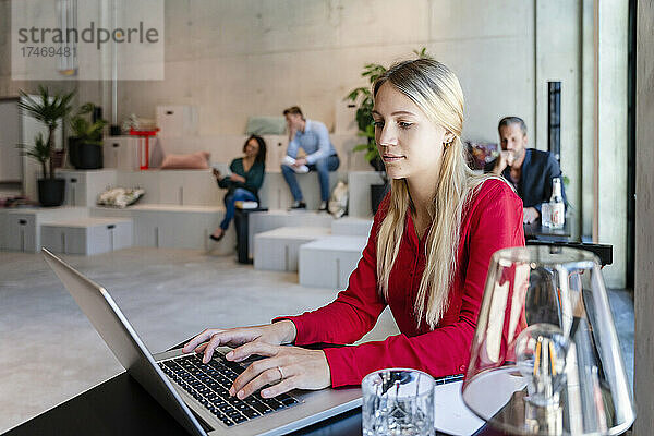 Blonde Geschäftsfrau benutzt Laptop am Schreibtisch