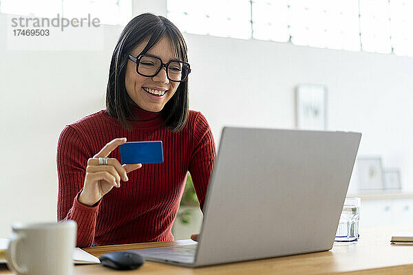 Glückliche berufstätige Frau  die online per Kreditkarte bezahlt