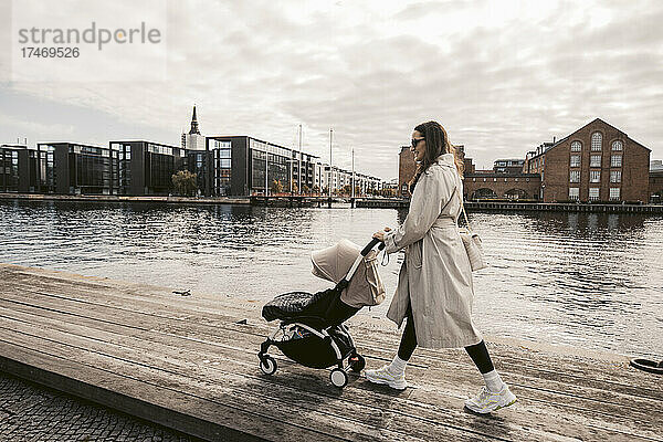 Frau geht mit Kinderwagen am Pier am Kanal in Kopenhagen  Dänemark