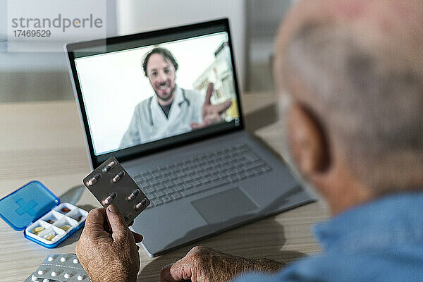 Älterer Mann nimmt medizinischen Rat per Videoanruf mit dem Arzt zu Hause entgegen