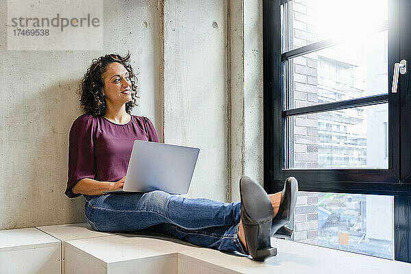 Lächelnde Unternehmerin mit Laptop im Büro