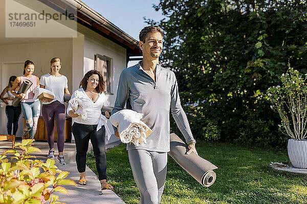 Männer und Frauen gehen auf dem Fußweg am Haus vorbei  während sie zum Yoga-Kurs gehen