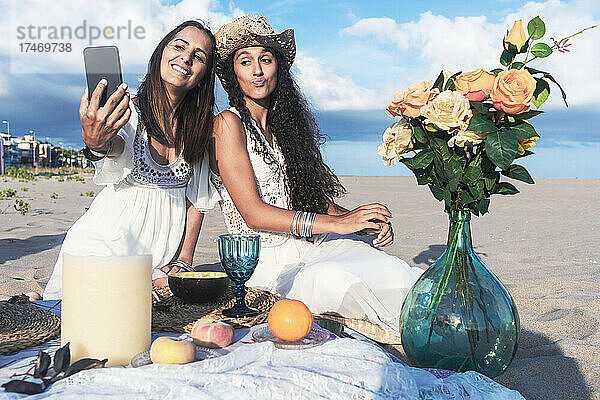 Frau macht Selfie mit Freundin per Smartphone am Strand