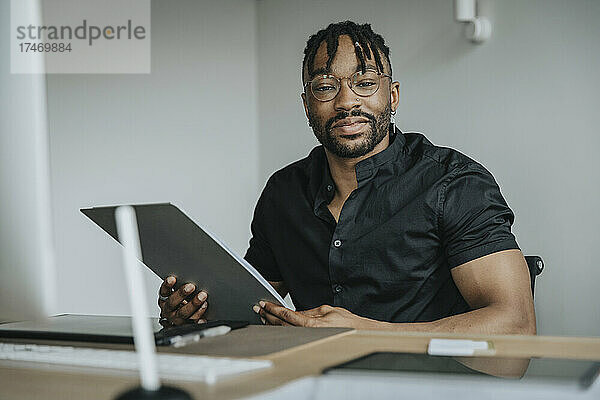 Geschäftsmann mit Brille hält Tablet-PC im Büro