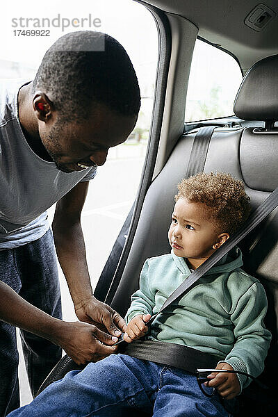 Vater passt Sicherheitsgurt seiner Tochter an  die im Auto sitzt